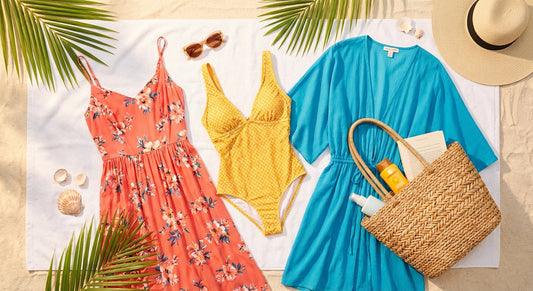 A bright, cheerful flat lay of a complete vacation wardrobe including a sundress, swimsuit, cover-up, and accessories arranged on a sandy beach towel in warm sunlight.